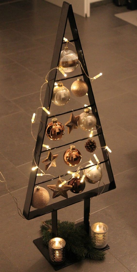 a blackened metal frame Christmas tree with lights, white, copper and brown ornaments plus candles at the base is a cool idea