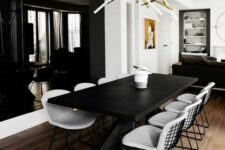a bold dining room with a black accent wall, a black table and white chairs, a bold and catchy chandelier
