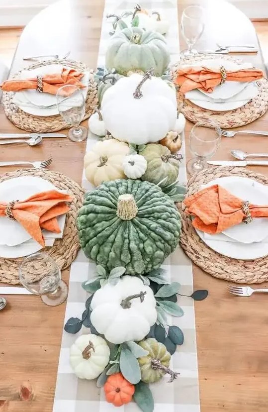a bright and fun Thanksgiving table with leaves, pastel and white pumpkins, woven chargers and orange napkins
