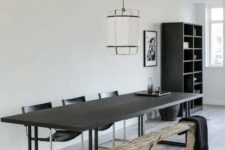 a catchy contemporary dining room with a black table, black leather chairs, a rustic wooden bench and a pendant lam[