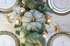 a chic green pumpkin Thanksgiving centerpiece with white hydrangeas and eucalyptus, pillar candles and gilded pears