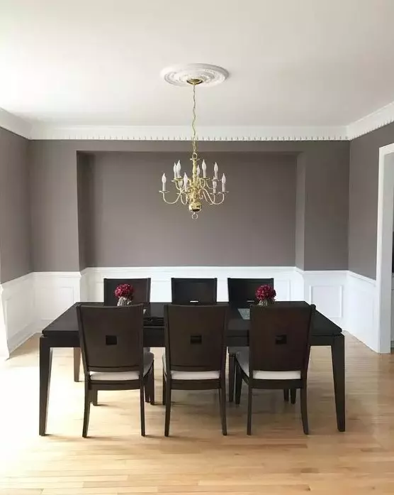 a clean mid-century modern to vintage dining room with creamy paneling, a black table and dark chairs, a gold chandelier