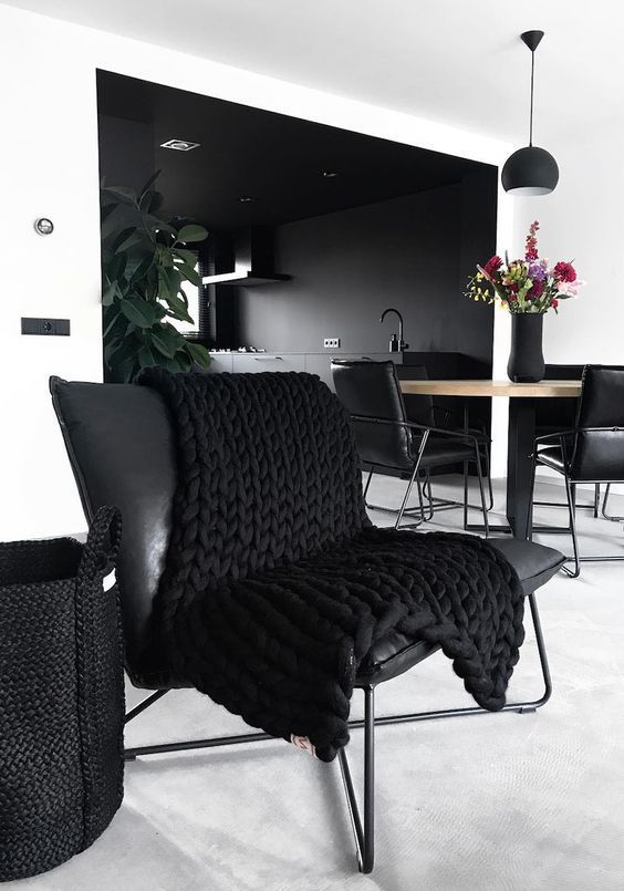 a contemporary black and white dining space with a round table, black leather chairs, a black pendant lamp