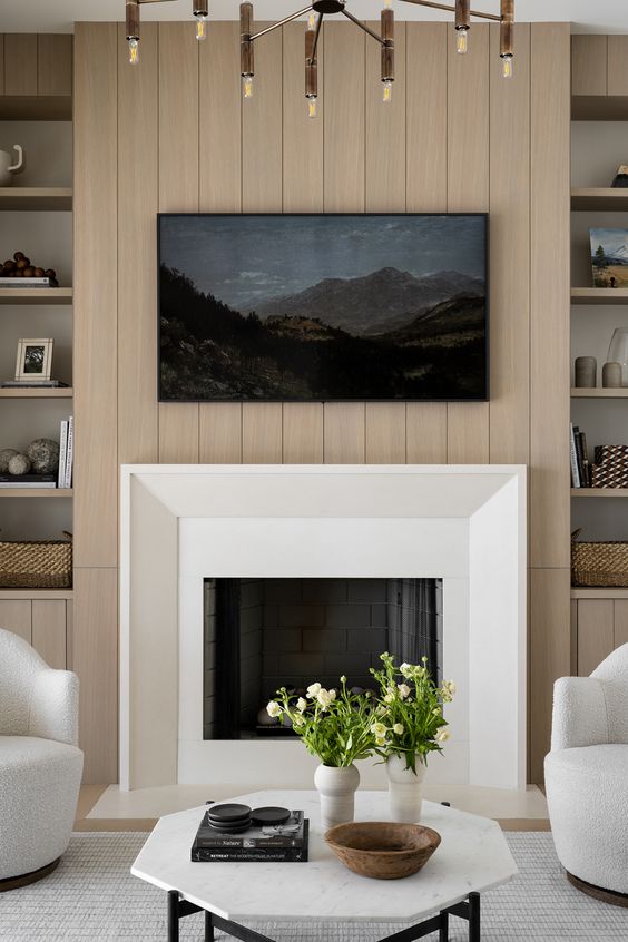 a contemporary living room with a shiplap wall and a built-in fireplace, creamy furniture and some built-ins