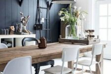 a contrasting monochromatic dining area with a black wall, a wooden table, white chairs, black pendant lamps