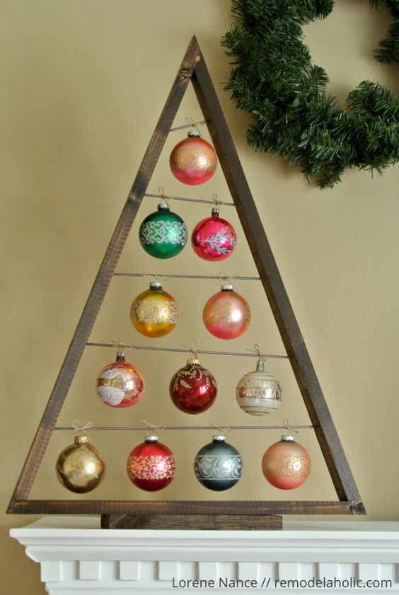 a dark-stained Christmas tree with colorful ornaments hanging is a stylish solution to decorate your Christmas mantel