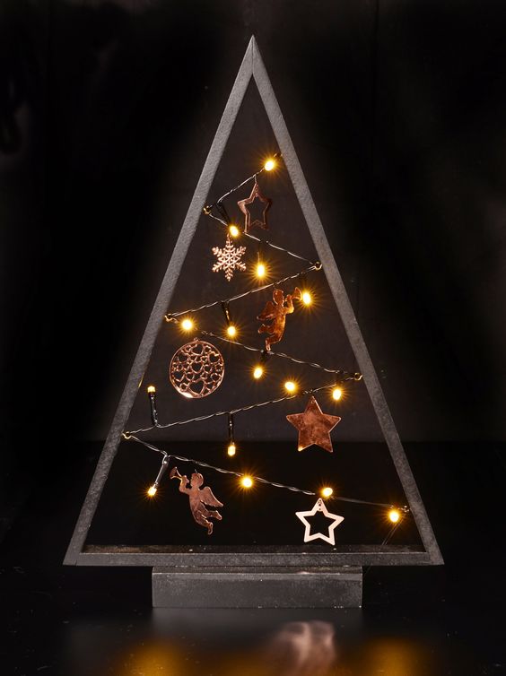 a dark-stained tabletop Christmas tree with lights, copper ornaments and stars is a cool and bold idea to place it somewhere on a mantel