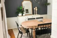 a farmhouse dining room with a grey accent wall, a vintage wooden dining table, black chairs and a bench, a vintage chandelier and a sideboard with some decor