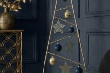 a gold metal Christmas tree with navy and gold ornaments and gold stars is a very chic and stylish idea for a modern space