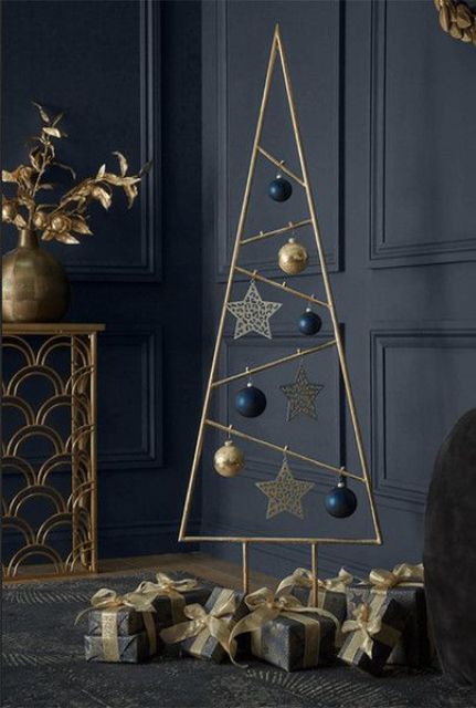 a gold metal Christmas tree with navy and gold ornaments and gold stars is a very chic and stylish idea for a modern space