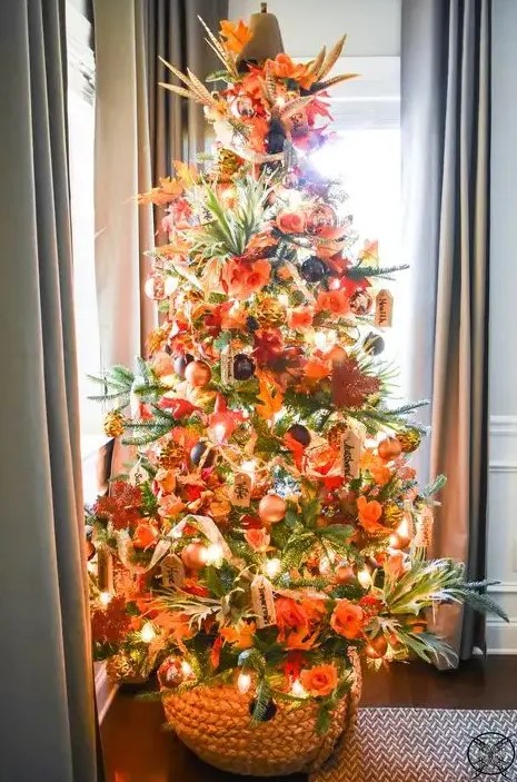 a gorgeous bright Thanksgiving tree with lights, orange, gold and black ornaments, faux leaves, foliage and a pumpkin on top