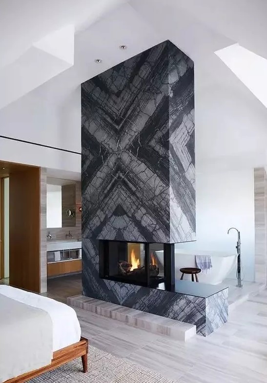 a grey marble slab fireplace separates the sleeping and bathing zone and makes them cozy and warm