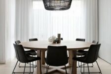 a laconic contemporary dining room with a round table, black chairs, a pendant lamp with a black woven lampshade is amazing