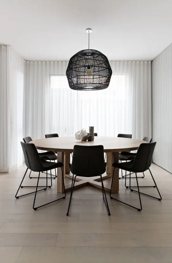 a laconic contemporary dining room with a round table, black chairs, a pendant lamp with a black woven lampshade is amazing