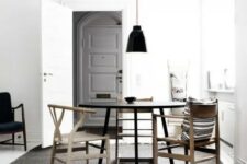 a laconic modern Scandi dining zone with a black round table, mismathing stained chairs and a black pendant lamp is amazing