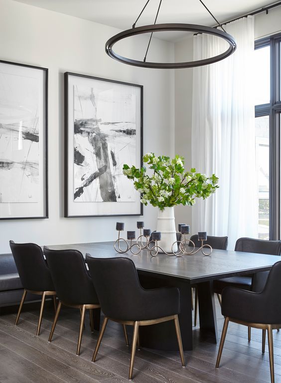 a light filled black and white dining room with white walls, a black table and chairs, a round chandelier and catchy artwork