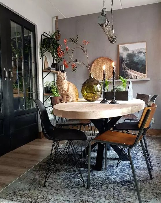 a lovely Scandinavian dining room with a taupe accent wall, a light-stained oval table, mismatching chairs and open shelving
