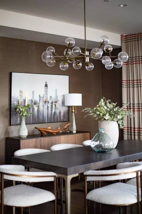 a mid century modern taupe dining room with a credenza, a dark table and creamy chairs, a lovely chandelier