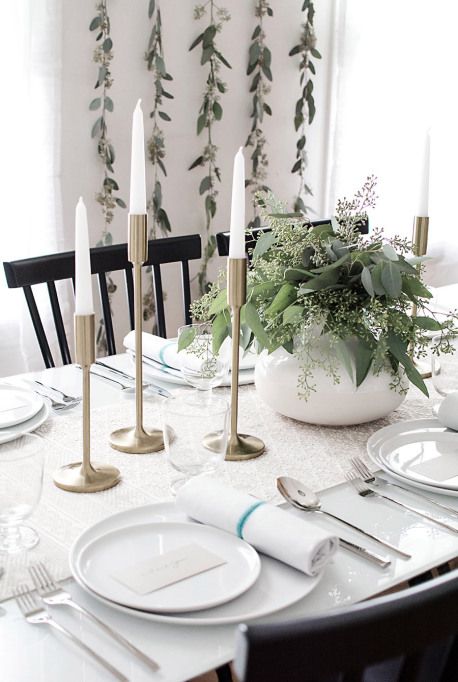 a minimalist and elegant Thanksgiving tablescape with a printed runner, white porcelain and napkins, gilded candleholders and tall and thin candles