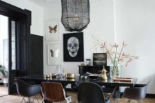 a modern Gothic dining room with white walls and a ceiling, black doors, a black table and chairs plus a pendant lamp