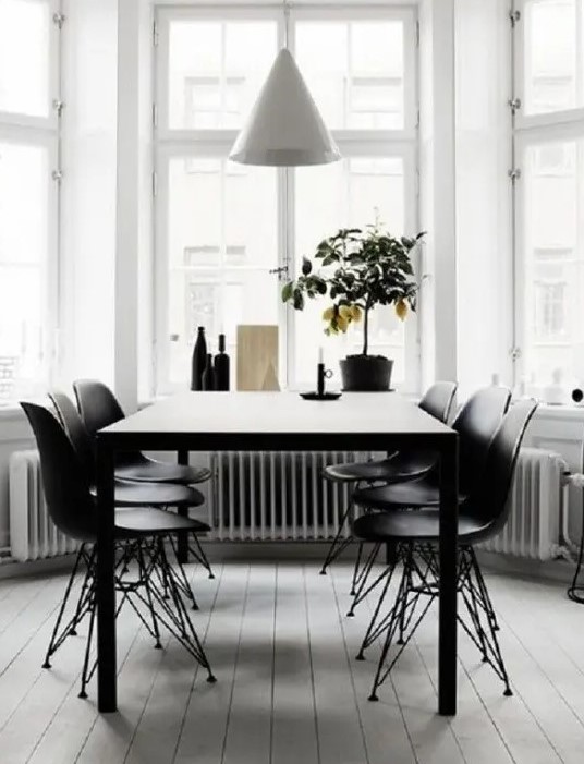 a modern dining space by the window, with a black table, black matching chairs and a white cone pendant lamp plus a lemon tree