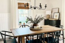 a modern farmhouse dining space with a stained table, black chairs, a black cabinet, a vintage chandelier and a printed rug