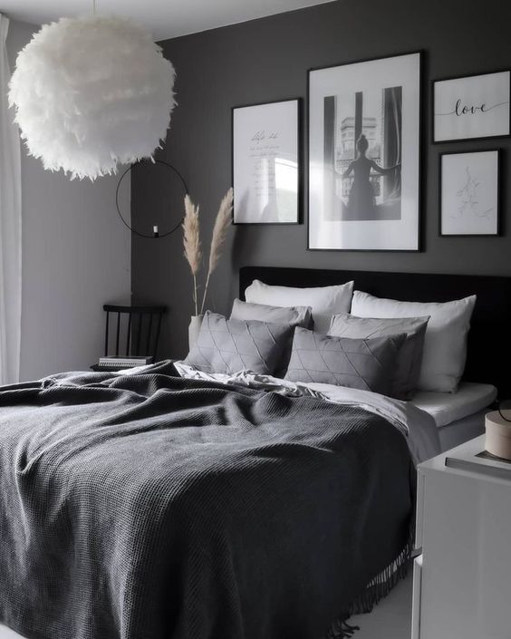 a monochromatic Scandi bedroom with a black accent wall, a black bed, monochromatic bedding, a gallery wall