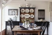 a monochromatic dining space with a black and stained wooden furniture, decorative plates and artworks