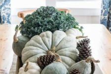 a natural Thanksgiving centerpiece of a bread bowl, pinecones, heirloom pumpkins, gourds and fresh veggies