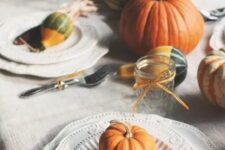 a natural tablescape with pumpkins, corn cobs, husks, candles and some elegant vintage plates
