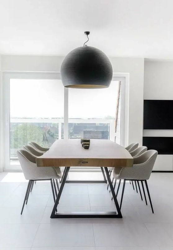 a pretty contemporary dining space with a living edge table, neutral chairs and a statement black pendant lamp is very cool