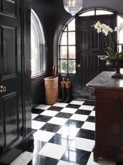a refined black and white foyer with checked floors, arched windows and black walls, a dark-stained storage unit