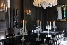 a refined black dining room with stucco, a niche with art, a glossy black table and lovely chairs, an oversized white chandelier