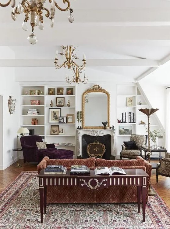 a refined vintage living room with a printed sofa, a purple lounger, leopard chairs, a fireplace, built-in shelves and a mirror in a gilded frame