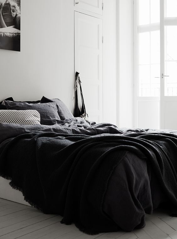 a relaxed Nordic bedroom with a bed with black bedding and a poster on the wall - who needs more for comfy sleeping