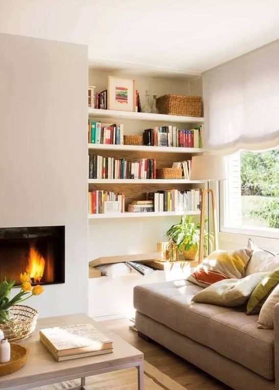 a sleek built-in fireplace, a bench and built-in shelves, a tan couch with pillows form a cozy and welcoming reading nook