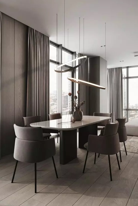 a sleek contemporary dining space with taupe wood panel walls, a large table and taupe chairs, lovely pendant lamps