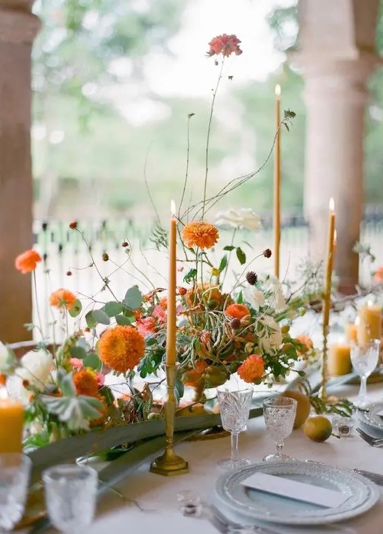 a sophisticated Thanksgiving tablescape with orange blooms and candles, with blue porcelain and orange candles