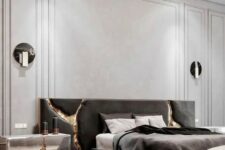 a sophisticated and luxurious contemporary bedroom with neutral paneled walls, a dark upholstered bed, various lamps and cracked touches with gold