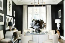 a sophisticated black and white dining room with black walls and a white ceiling, a round white table and catchy chairs, a lovely console table and gilded touches
