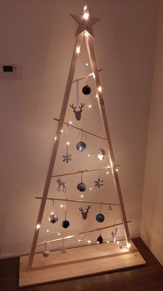 a stained frame Christmas tree with lights, irregularly placed railings, white, black and silver ornaments of various shapes