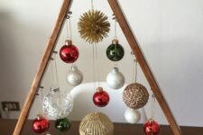 a stained tabletop Christmas tree with white, red, gold and clear ornaments hanging down is a bright and cool decoration