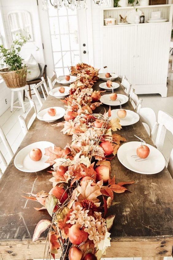 a super simple Thanksgiving table runner of faux leaves, blooms and apples, all done in rust, terracotta and brownish shades