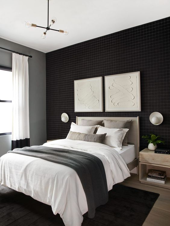 a welcoming bedroom with a black accent wall, a grey bed with neutral bedding, stained nightstands and a black rug