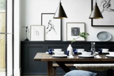 a welcoming black and white dining room with black paneling, a stained table and benches, a gallery wall and pendant lamps