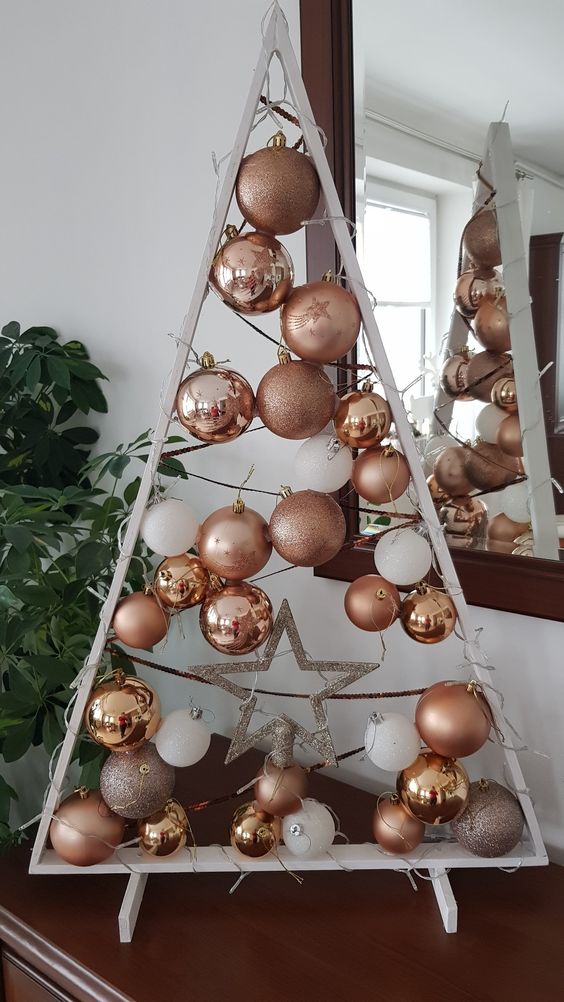 a white frame Christmas tree with threads, copper, rose gold and white ornaments hanging plus a silver star is cool