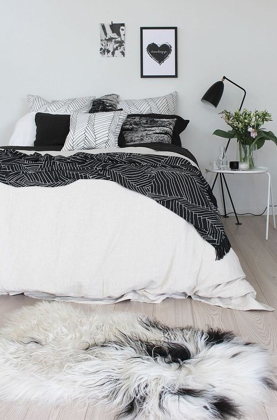 an airy Scandinavian bedroom with just some black touches for soem drama - a lamp, bedding and an artwork