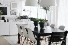an airy Scandinavian dining room with a black table, white and black chairs, white pendant lamps and a pretty and very simple rug