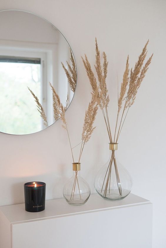 minimalist Thanksgiving decor with clear vases with gold touches and dried grasses, a black candle is a lovely and easy to repeat idea