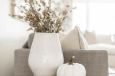 super easy and minimal Thanksgiving decor with a stack of books, some dried flowers in a vase and a white pumpkin